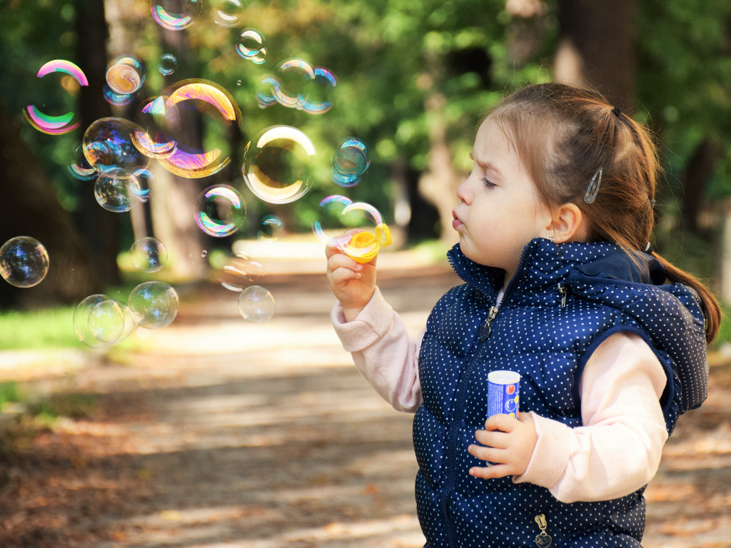girl blowing bubbles outside