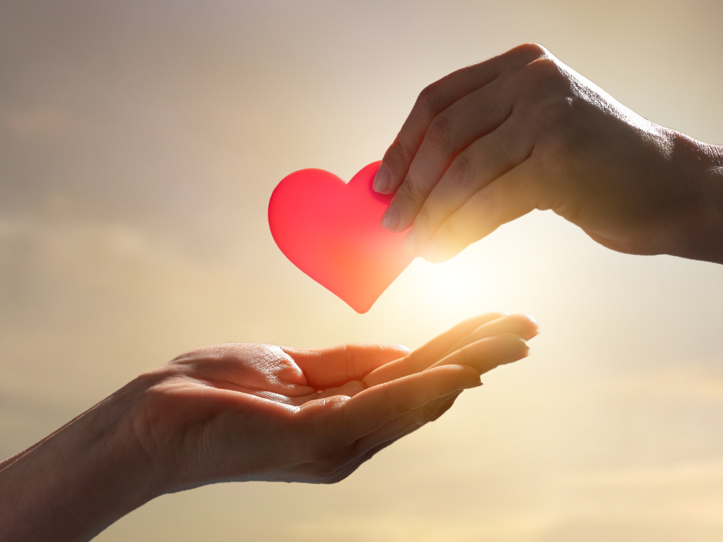 one hand giving another a heart donation