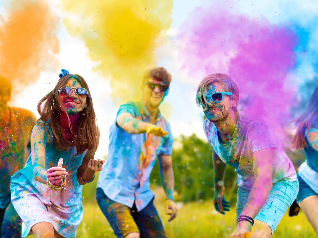 three people throwing color powder